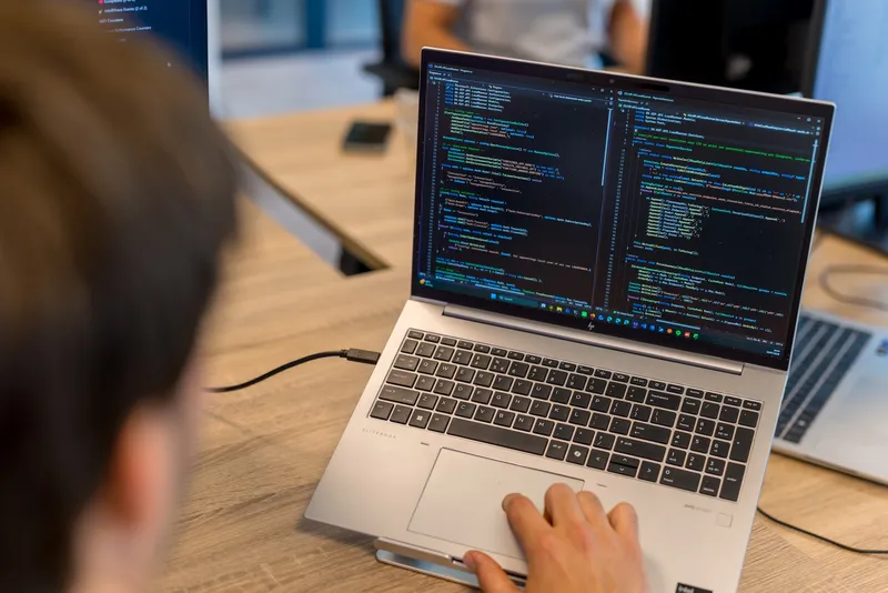 AutoMapper’s Licensing and Security Dilemma Close-up van een computerscherm met C#-code en Nederlandse commentaren in een donkere code-editor, gefotografeerd vanuit een hoek in een kantooromgeving.