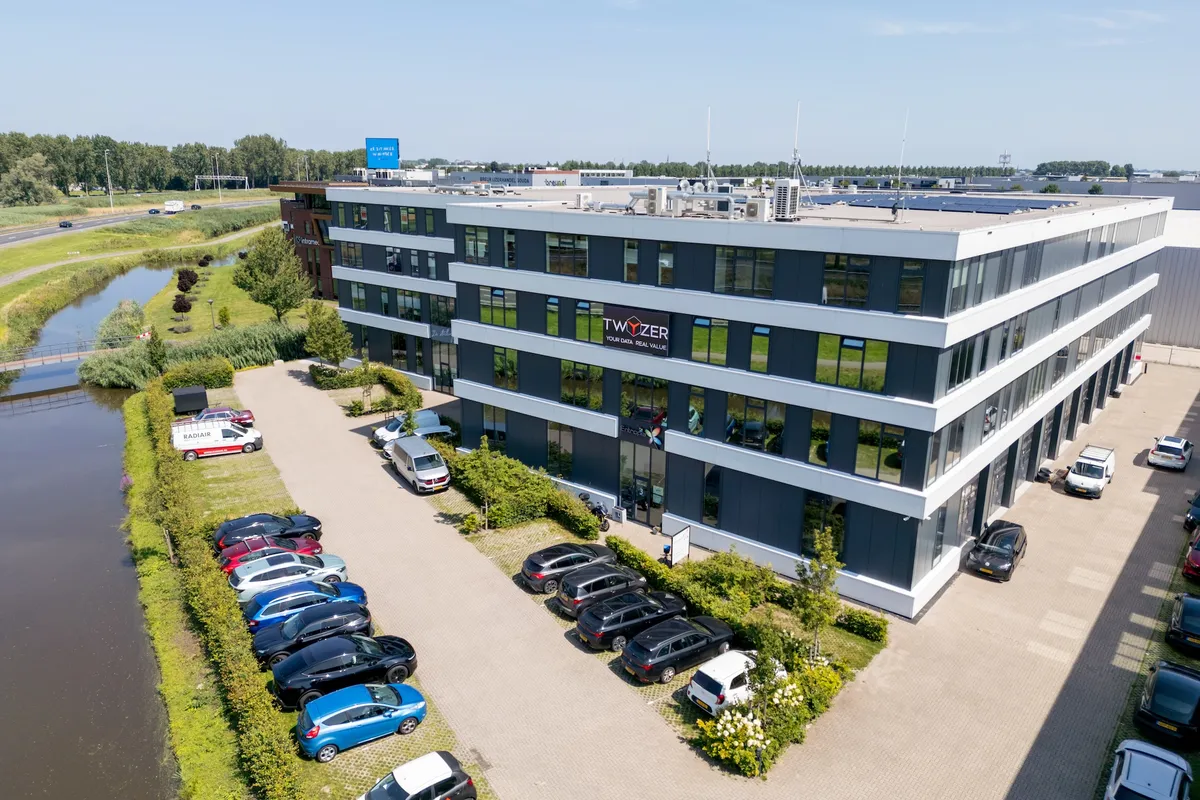 Luchtfoto van het Twyzer-kantoor met slogan Your Data. Real Value. op de gevel, omringd door groen en parkeerplaatsen